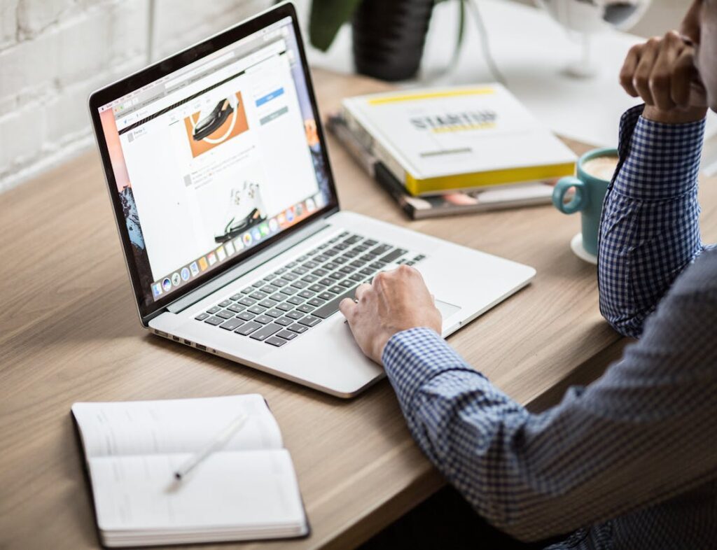 A person working on a laptop at a wooden desk